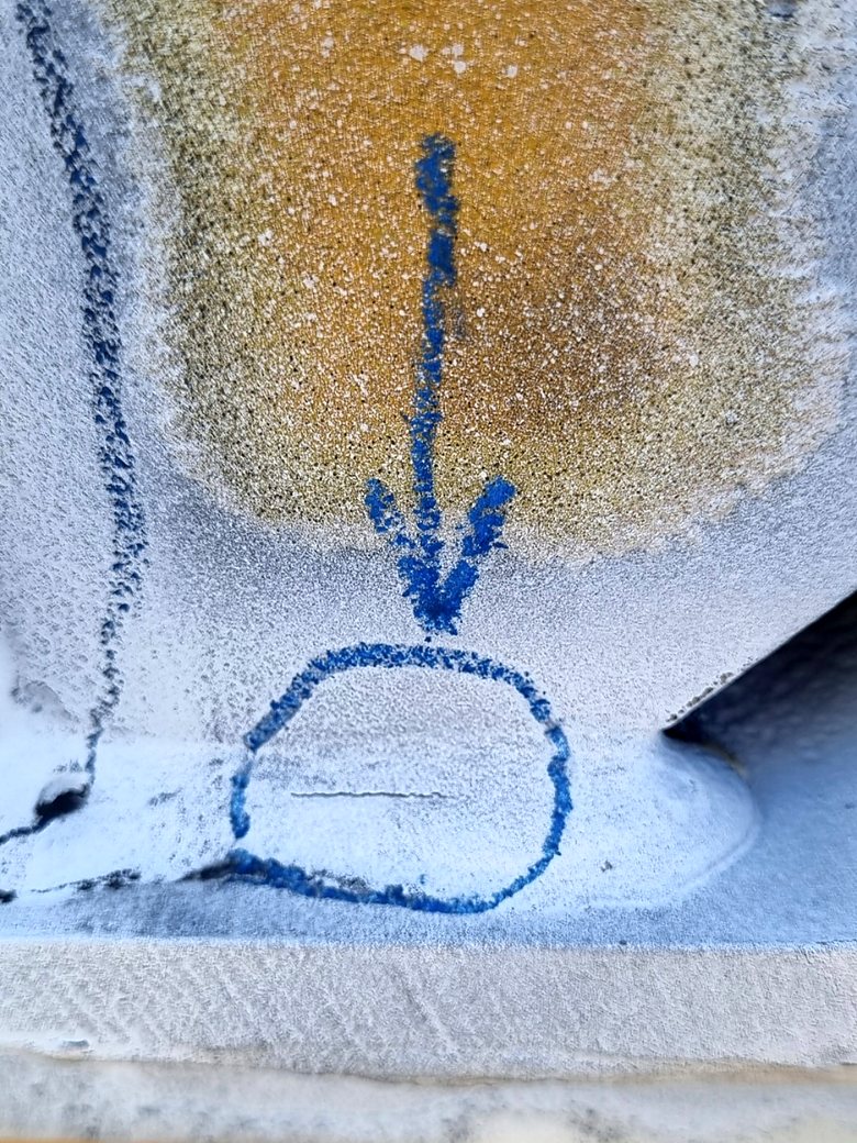 Magnetic particle indication on a weld, circled and arrowed in blue chalk for repair