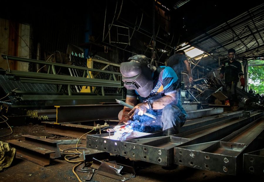 Welder fabricating structural steel beams in a workshop